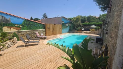 Espace piscine Le N°9 à Argeliers avec piscine turquoise, terrasse en bois, transats et murs en pierre