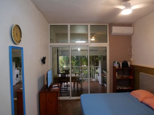 Studio apartment in Saint-François with blue bed, wooden furniture, glass doors opening to terrace with sea view, AC unit,