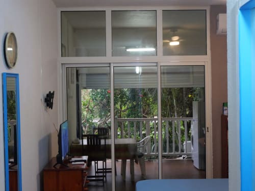 Studio apartment interior at Face Marina in Saint-François with glass doors opening to lush garden terrace view