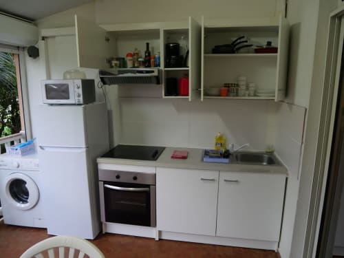 Compact equipped kitchen in Studio Face Marina apartment, Saint-François with white cabinetry, stovetop, sink, and open