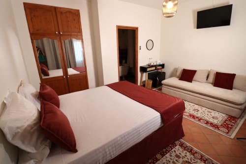 Chambre double avec terrasse à l'Hôtel Villa Roseraie à Vence, avec lit à chemin rouge, canapé, armoire en bois et jardin