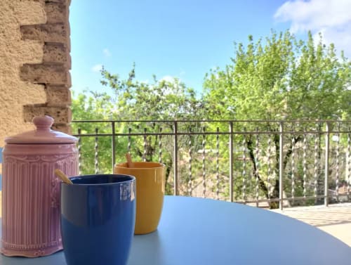 Stoviglie colorate sul tavolo della terrazza con vista sul paesaggio verde a Casa gli Archi sul Borgo, Campagnano di Roma