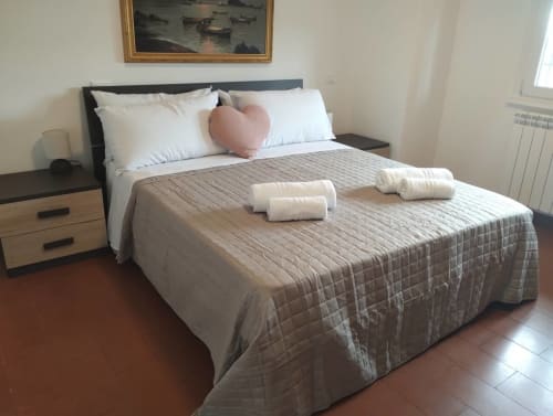 Letto ben preparato con trapunta grigia trapuntata e cuscini bianchi a Casa gli Archi sul Borgo a Campagnano di Roma, Italia