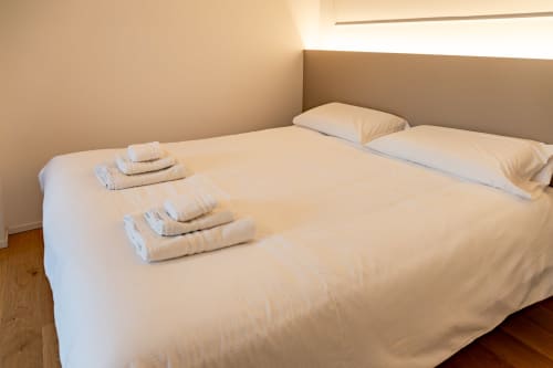 Spacious bedroom in Ca' Borsa IV suite at Treviso Stays with neatly arranged white towels on a large bed and pillows.