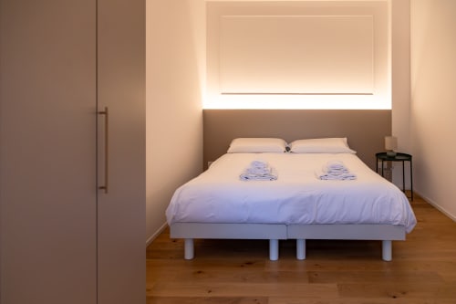 Camera moderna presso Treviso Stays con letto bianco, testiera marrone, pavimento in legno, opere d'arte murale illuminate e guardaroba a Ca'