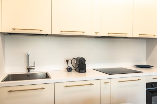 Cucina moderna a Treviso Stays con mobili color panna, lavello in acciaio inox, piano di lavoro bianco e elettrodomestici neri
