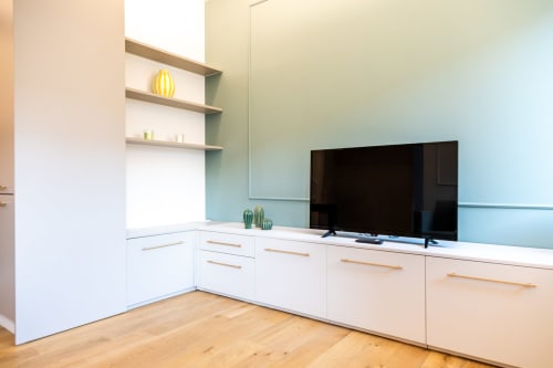 Cucina moderna con armadi bianchi, TV a schermo piatto e pareti verde salvia nell'appartamento Treviso Stays, Treviso