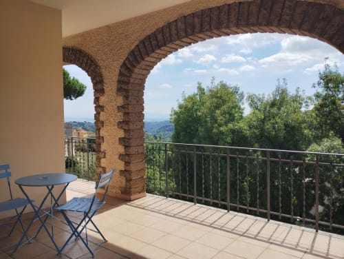 Terrazza con volta in mattoni affacciata su colline ondulate, sedie blu e ringhiera in metallo a Casa gli Archi, Campagnano di Roma