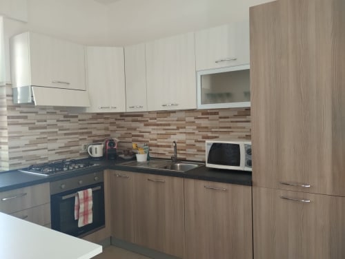Cucina moderna nell'appartamento Casa gli Archi sul Borgo a Campagnano di Roma, con mobili color crema e legno, piastrelle righe e