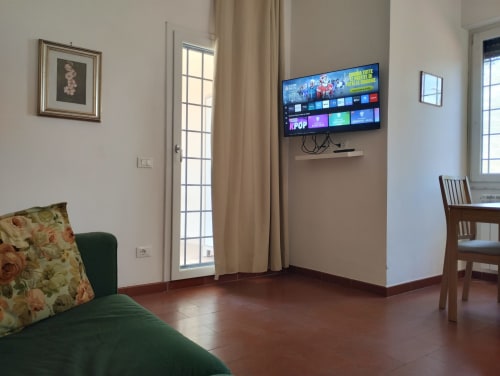 Soggiorno moderno a Casa gli Archi sul Borgo con divano verde, TV a schermo piatto e pavimenti in terracotta