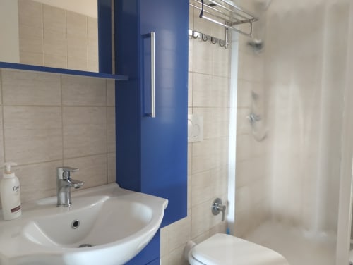 Bagno moderno con parete azzurra, lavabo bianco e doccia a Casa gli Archi sul Borgo, Campagnano di Roma