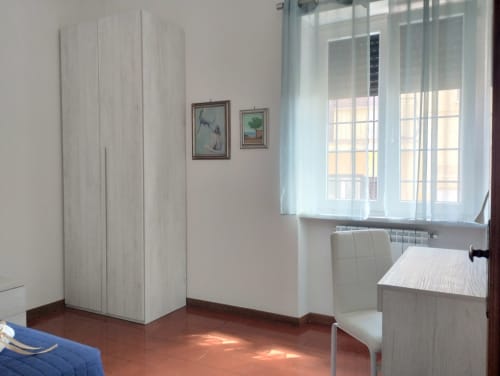 Luminosa camera da letto a Campagnano di Roma con armadio bianco, pavimento in cotto e finestra con vista sul giardino