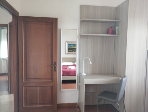 Moderna camera da letto con angolo di lavoro, scrivania, sedia, libreria e specchio nell'appartamento Casa gli Archi sul Borgo a Campagnano di