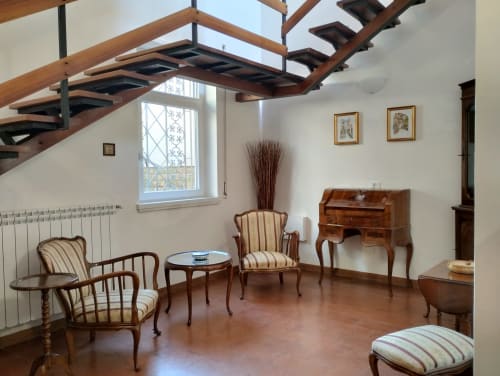 Elegante soggiorno con travi in legno, poltrone righe e mobili d'epoca nell'appartamento di Campagnano di Roma