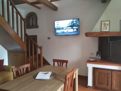 Ampia zona living in Casina Bella Vista a Roma, con travi in legno, scala, TV e comfort moderni