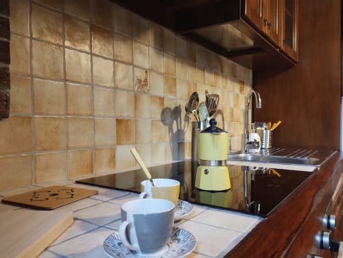 Cucina Casina Bella Vista a Campagnano di Roma con rivestimento piastrellato, moka verde e tazze di caffè al bancone