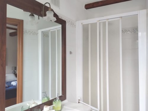 Bagno moderno in appartamento Casina Bella Vista con doppio lavabo, specchi grandi, doccia aperta e travi in legno