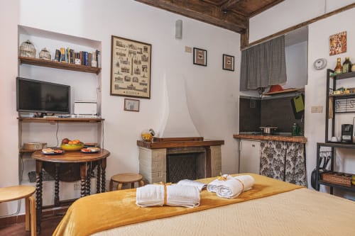 Camera da letto accogliente a Roma con camino, travi in legno, TV e servizi benvenuto presso Casa Pettinari 78