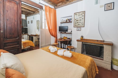 Camera da letto accogliente in Casa Pettinari, Roma con camino, travi in legno e dettagli arancioni
