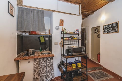 Kitchenette compatta nell'appartamento romano con lavello, piano cottura, forno a microonde, scaffali in legno e arredamento vintage a Casa Pettinari 78