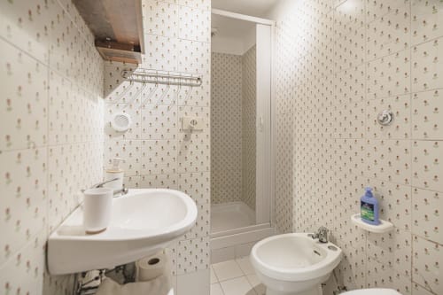 Bagno compatto di Casa Pettinari 78 a Roma con lavabo angolare, bidet, cabina doccia e piastrelle beige.