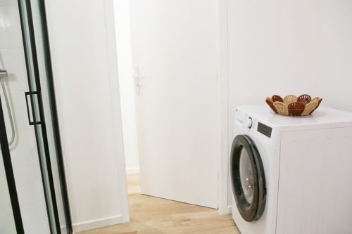 Modern laundry room in Wellkhome Appartements Bordeaux with white washing machine and woven storage basket on top