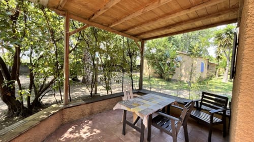 Veranda con pergolato in legno, tavolo da pranzo e sedie con vista sul giardino del Maquis Plage, Poggio-Mezzana