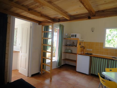 Cucina luminosa con travi in legno, rivestimento in piastrelle gialle e vista sul giardino dell'hotel Le Maquis Plage a Poggio-Mezzana