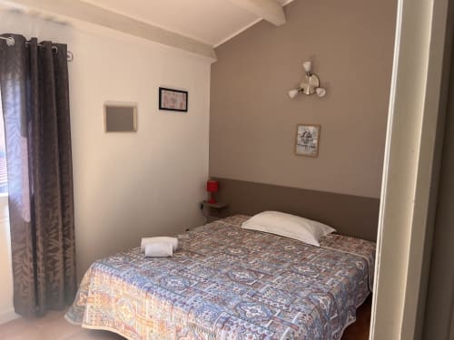 Camera accogliente all'hotel Le Maquis Plage a Poggio-Mezzana con coperta a fantasia, cuscino bianco e arredamento neutro.