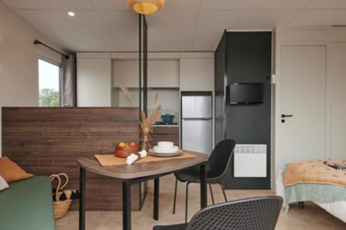 Studio Mobil-Home Bambou à Le Maquis Plage avec table à manger, kitchenette et chambre à Poggio-Mezzana