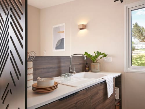 Évier de cuisine moderne avec meubles en bois et plan de travail blanc à la villa Bambou du Maquis Plage, Corse
