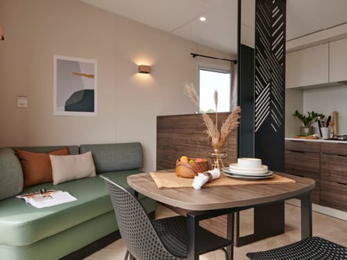 Studio moderne au Maquis Plage avec séjour ouvert, canapé vert, table à manger, kitchenette et décoration contemporaine