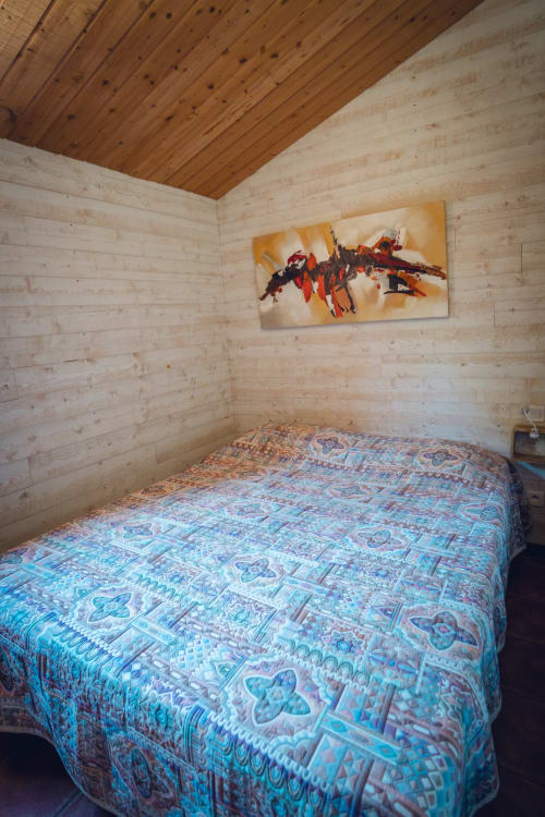 Chambre cosy en bois de la villa Le Maquis Plage avec dessus-de-lit à motifs et art mural abstrait moderne