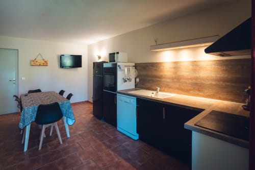 Cuisine et salle à manger modernes d'une villa à Le Maquis Plage, avec mobilier bleu et noir, crédence en bois