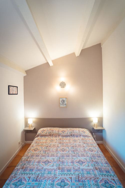 Chambre moderne de la villa Le Maquis Plage avec literie à motifs, éclairage ambiant et plafond mansardé à Poggio-Mezzana