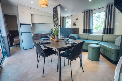 Espace de vie moderne ouvert au Mobil-Home Yuka, Le Maquis Plage : table à manger, cuisine et canapé vert