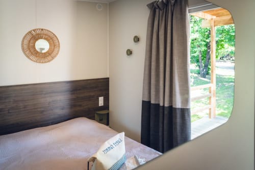 Modern bedroom at Le Maquis Plage hotel in Poggio-Mezzana with dark wood headboard, coastal-style decor, and garden view