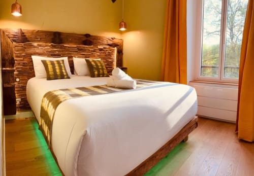 Chambre luxueuse au Moulin du Guy à Chanverrie avec tête de lit en bois, draps blancs et murs ambré chaud