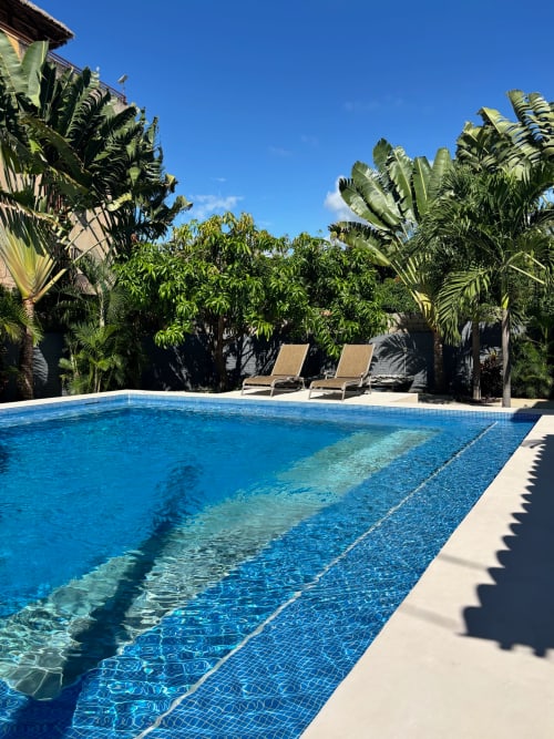 Piscina tropical en Calilla & Tsuki, Puerto Escondido, con palmeras, tumbonas y agua cristalina