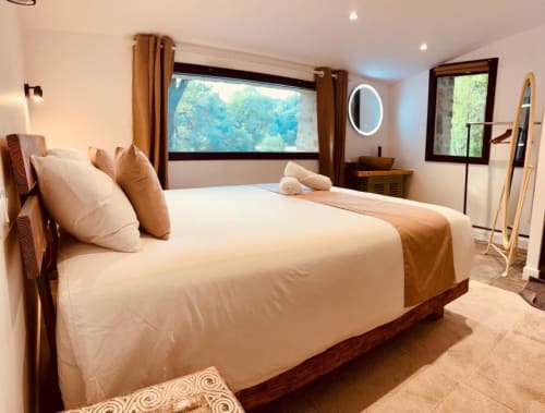Spacieuse chambre à coucher du gîte Le Moulin du Guy avec vue sur la rivière, literie crème, mobilier en bois et écran plat