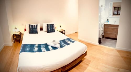 Chambre zen du gîte Le Moulin du Guy à Chanverrie avec literie blanche, oreillers bleus, parquet et salle de bain attenante