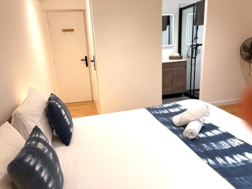 Chambre moderne au Gîte Le Moulin du Guy à Chanverrie avec lit blanc, oreillers bleu marine et salle de bains attenante