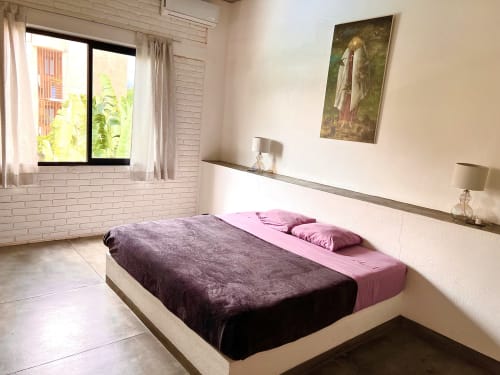 Habitación moderna con ropa de cama gris oscuro y rosa, paredes de ladrillo blanco y ventana con vista al mar en la casa Casa Tsuki, Puerto Escondido