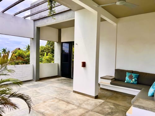 Patio moderno de la casa Tsuki en Puerto Escondido con asientos de descanso, pérgola, vista al mar y plantas tropicales