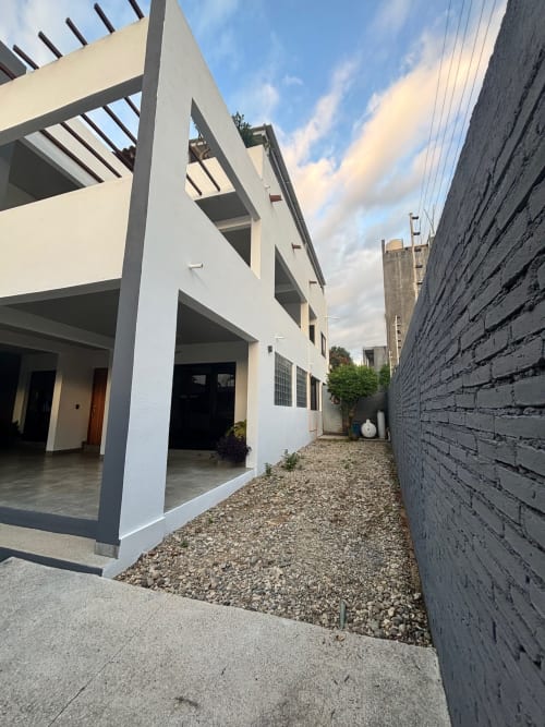Casa Tsuki, moderna cabaña blanca en Puerto Escondido con pérgola, patio de grava y muro de ladrillo oscuro