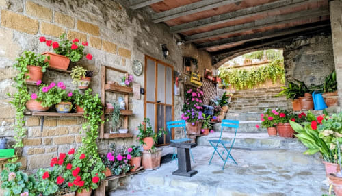 Charming Italian villa terrace with blooming flowers, stone walls, wooden door, and blue chairs overlooking the lake