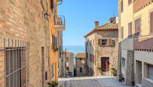 Charming Italian stone village street with historic buildings and lake view in background