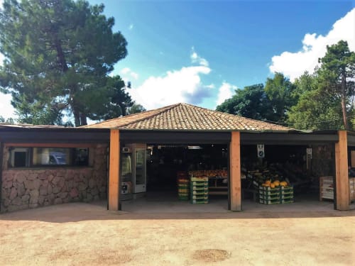 Alma Rossa roadside produce stand in Lecci with pyramidal roof, wooden pillars, and fruit displays