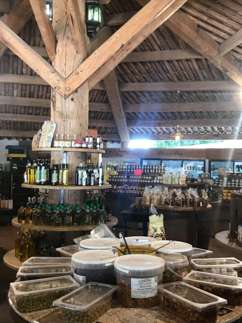 Rustic tasting room at ALMA ROSSA in Lecci with exposed wooden beams, olive oil bottles, and local products displayed on