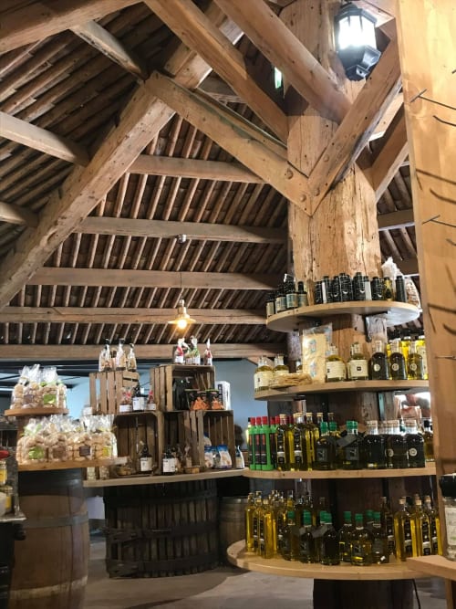 Rustic shop interior at ALMA ROSSA Lecci with exposed wooden beams, olive oil bottles, and local products on display shelves